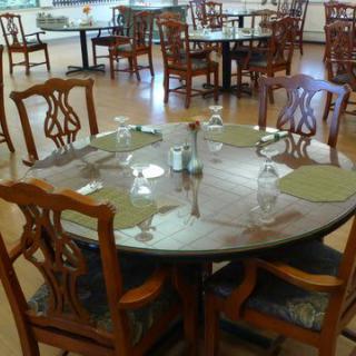 A neatly set round dining table with wooden chairs in a restaurant.