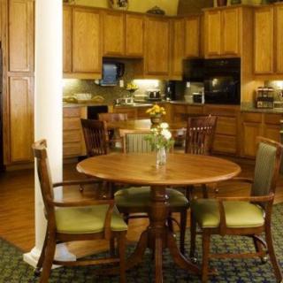 A cozy kitchen and dining area with wooden cabinets, a round table, and chairs.