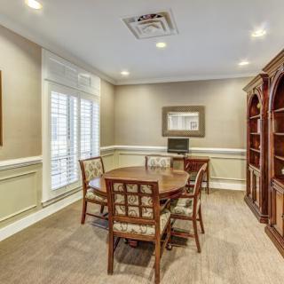 A well-furnished dining room with a round table, chairs, and a wooden bookshelf.