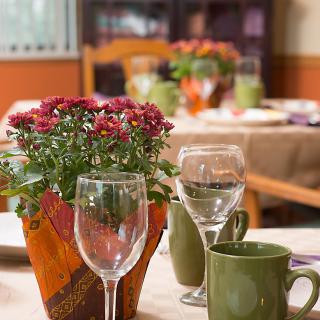 A beautifully set dining table with flowers, wine glasses, and mugs.