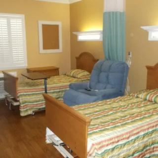 A hospital room with two beds and a reclining chair.