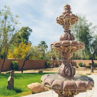 A beautiful stone fountain in a landscaped garden.