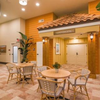 A cozy lobby area with tables and chairs, featuring warm lighting and decorative plants.