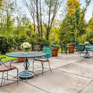 A tranquil outdoor patio with tables and chairs surrounded by lush greenery.