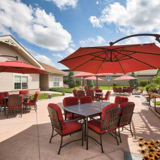 An outdoor patio area with red umbrellas and seating under a cloudy sky.