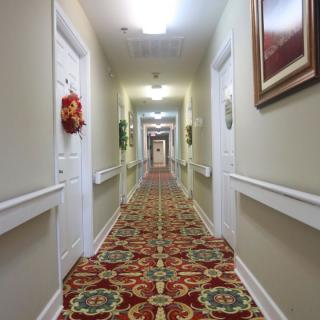 A long, decorated hallway with patterned carpet and multiple doors on each side.