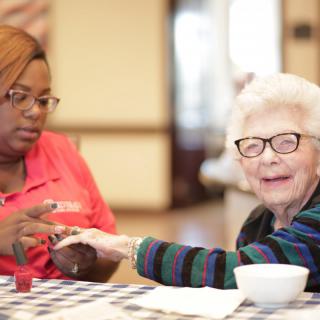 A caregiver assisting an elderly woman at a nursing home.