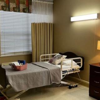 A hospital room with a bed, curtains, and a lamp.