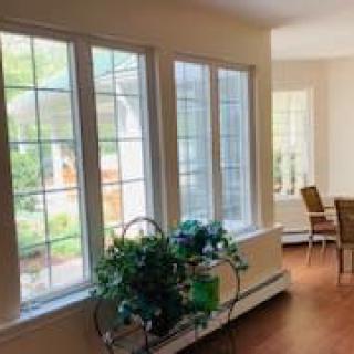 A bright interior space with large windows, plants, and a dining area.