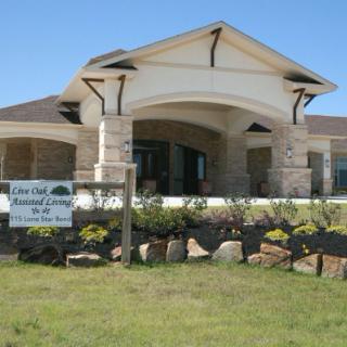 A modern building with a landscaped front and a sign on the lawn.