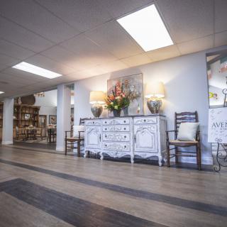 A spacious and stylishly decorated interior featuring a white sideboard with floral decor, wooden chairs, and ambient lighting on a wooden floor.