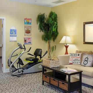A cozy living room featuring an elliptical machine alongside comfortable seating and warm lighting.