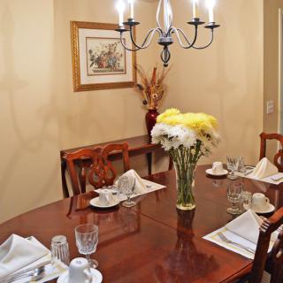 A neatly set dining table with flowers and a chandelier overhead.