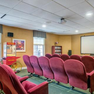 A cozy home theater with red seating and a popcorn machine.