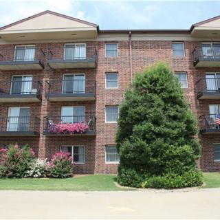 A brick apartment building with balconies and landscaped surroundings.