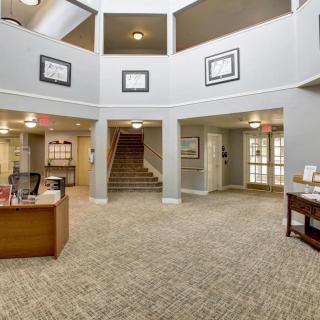 A spacious office lobby with a reception desk, carpeted floors, and central stairs.