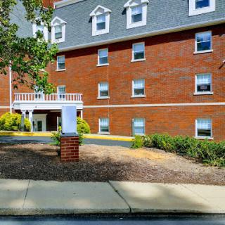 A brick building featuring multiple windows and a landscaped entrance.