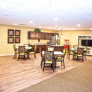 An open concept living space featuring a kitchen, dining area with tables and chairs, and a television.