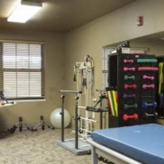 A therapy room equipped with various exercise tools, including dumbbells and an exercise ball.