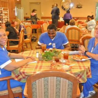 Healthcare workers in blue scrubs enjoying a meal together in a dining area.