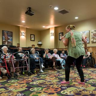 A group of seniors participating in an indoor activity led by an instructor.