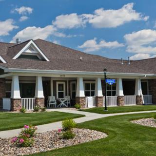 A suburban house with a manicured lawn under a clear blue sky.