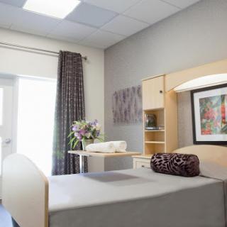 A well-designed patient room featuring a bed, decorative artwork, and fresh flowers.