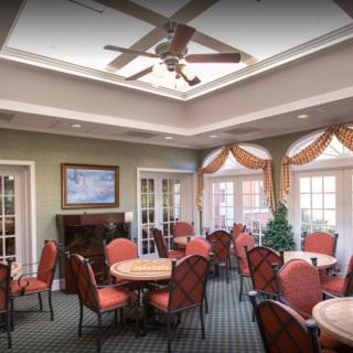 A well-decorated dining room with multiple tables and chairs, featuring a ceiling fan and decorative elements.