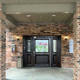 Front entrance of a brick building with double doors and a covered porch.