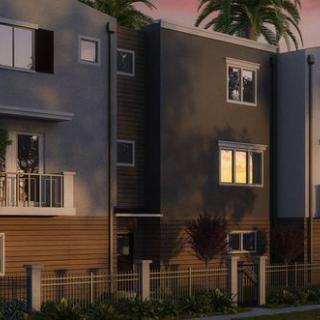A modern multi-story house with palm trees at sunset.