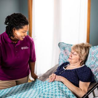 A caregiver provides support and companionship to an elderly patient in a home setting.