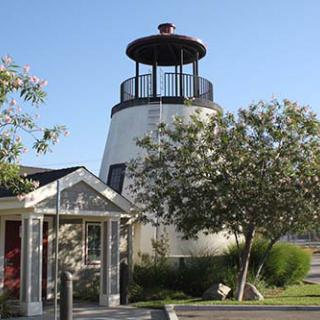 A picturesque lighthouse surrounded by greenery and clear skies.