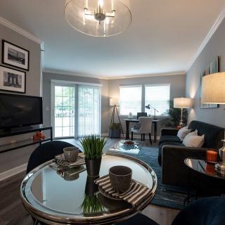 A modern living room with stylish decor, featuring a sofa, glass table, and a TV.