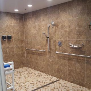 A spacious, accessible walk-in shower with handrails and tiled walls.
