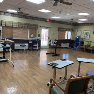 A spacious rehabilitation therapy room equipped with various medical instruments and furniture.