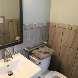 A modern bathroom with a sink, mirror, and neatly folded towels on the toilet.