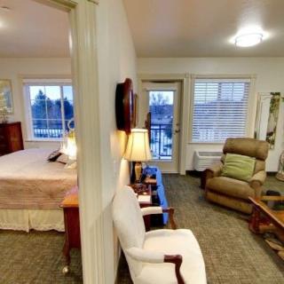 A cozy interior view featuring a living area with chairs and a lamp, adjacent to a bedroom.