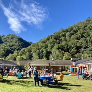 A vibrant outdoor gathering set against a picturesque mountain backdrop, filled with families enjoying activities and each other's company.