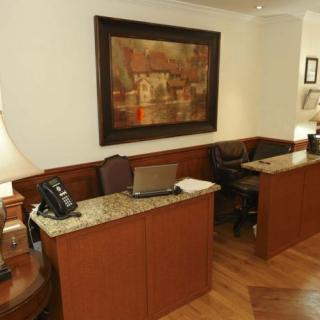 A reception area with wooden desks, laptops, and a telephone, adorned with artwork on the wall.