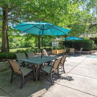 An outdoor patio area with tables, chairs, and umbrellas under a sunny sky.