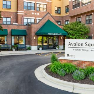 Entrance to Avalon Square residential apartments with green canopies and landscaped surroundings.