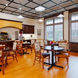 A cozy cafe interior with neatly arranged tables and chairs, featuring a modern design and wooden flooring.