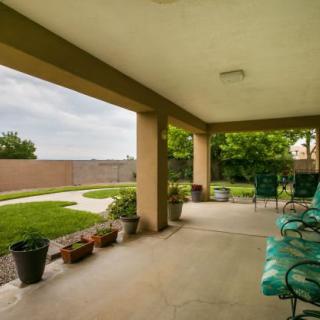A covered patio with seating and a view of the backyard garden.