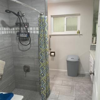 A modern bathroom with a tiled shower area and patterned shower curtain.