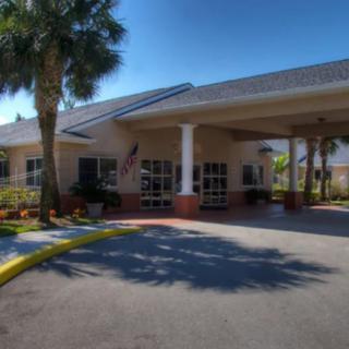 A building entrance with a covered walkway and palm trees on a sunny day.