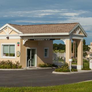 A small building with a covered entrance and driveway, set against a clear sky.