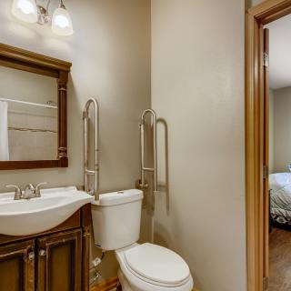 A cozy bathroom with a sink, toilet, and mirror, featuring warm lighting.