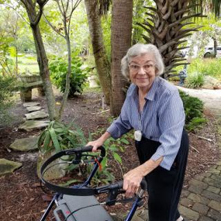 An elderly woman joyfully using a walker while enjoying the serene outdoors.