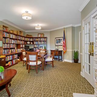 A well-organized office space featuring bookshelves, a desk, chairs, and an American flag.