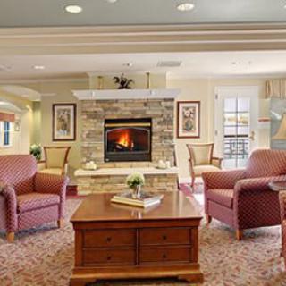 A cozy living room with a central fireplace, surrounded by comfortable armchairs and a wooden coffee table.